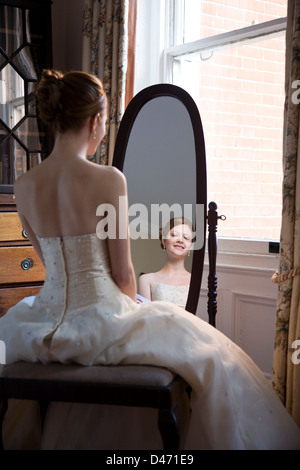 Vista posteriore si riflette nell'ovale specchio di lunghezza completa di dai capelli rossi sposa in crema senza spalline abito da sposa Foto Stock