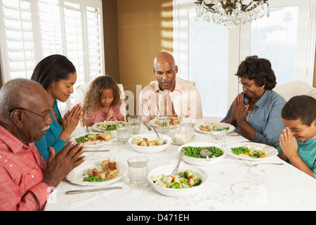 Generazione Multi Family dicendo grazia prima di pasto a casa Foto Stock