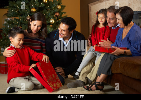 Multi generazione apertura famiglia Regali di natale nella parte anteriore della struttura ad albero Foto Stock