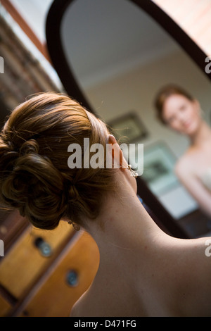 Vista posteriore si riflette nell'ovale specchio di lunghezza completa di dai capelli rossi sposa in crema senza spalline abito da sposa Foto Stock