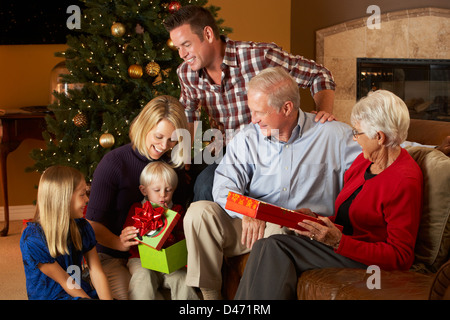 Multi generazione apertura famiglia Regali di natale nella parte anteriore della struttura ad albero Foto Stock