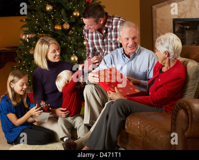 Multi generazione apertura famiglia Regali di natale nella parte anteriore della struttura ad albero Foto Stock