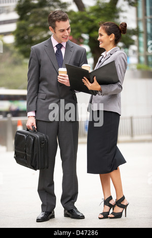 Imprenditore e imprenditrice discutendo documento nella tenuta di strada di caffè da asporto Foto Stock