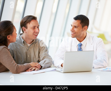 Medico utilizzando laptop a discutere il trattamento con pazienti Foto Stock