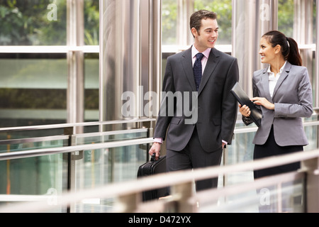 Due colleghi di lavoro avendo discussioni mentre passeggiate al di fuori ufficio Foto Stock