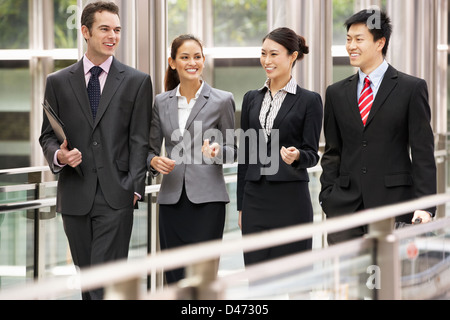 Quattro colleghi di lavoro avendo discussioni mentre passeggiate al di fuori ufficio Foto Stock