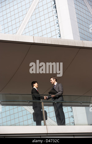 Due imprenditori si stringono la mano al di fuori di Edificio per uffici Foto Stock