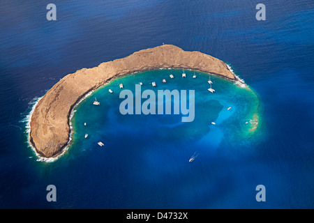 Molokini cratere, antenna colpo di forma di una mezzaluna isolotto a metà mattina con barche a noleggio, Maui, Hawaii. Foto Stock