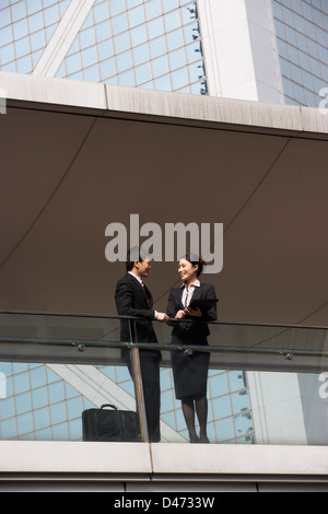 Due colleghi di lavoro avente la discussione al di fuori ufficio edificio Foto Stock