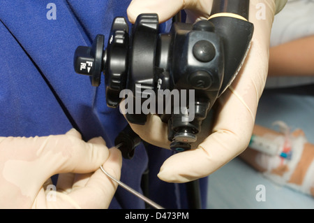Un chirurgo utilizzando un endoscopio, dispositivo con una luce e telecamera in miniatura, per eseguire visual esami interni e biopsie Foto Stock