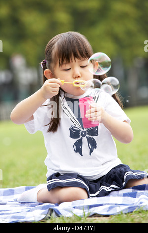 Giovane ragazza cinese in Park a soffiare bolle Foto Stock