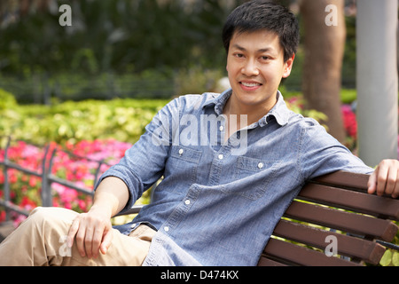 Giovane uomo cinese relax su una panchina nel parco Foto Stock