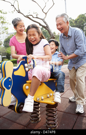 Nonni cinese a giocare con i nipoti nel parco giochi Foto Stock