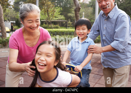 Nonni cinese a giocare con i nipoti nel parco giochi Foto Stock