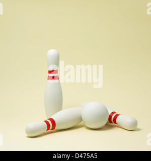 Tre bianco e rosso caduti a birilli con sfera tagliata su sfondo bianco Foto Stock