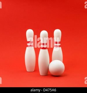 Tre bianco e rosso birilli con sfera tagliata su sfondo rosso Foto Stock