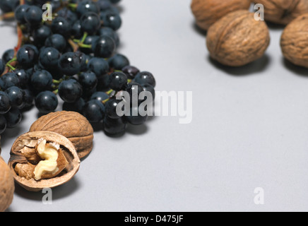 Immagine ravvicinata di uva e noci tagliate fuori lo sfondo grigio Foto Stock