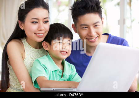 Famiglia cinese seduto alla scrivania con computer portatile a casa Foto Stock