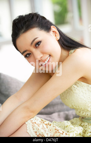 Giovane donna cinese rilassante sul divano di casa Foto Stock