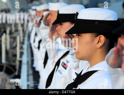 Marinai e Marines rendere onora come USS Ronald Reagan passa la USS Arizona Memorial Foto Stock