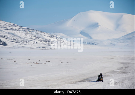 Un cavaliere solitario su una motoslitta nel deserto al di fuori di Longyearbyen su Spitsbergen in Svalbard Norvegia nel maggio Foto Stock