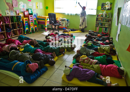 Giovane Sudafricano bambini sdraiarsi su stuoie per un sonno durante il tempo di riposo in uno sviluppo della Prima Infanzia centro di Città del Capo Foto Stock