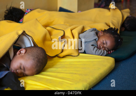 Giovane Sudafricano bambini sdraiarsi su stuoie per un sonno durante il tempo di riposo in uno sviluppo della Prima Infanzia centro di Città del Capo Foto Stock