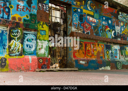 Pastore Tedesco cane dietro un cancello con parete parete colorati graffiti in vero La Boca, Argentina Foto Stock