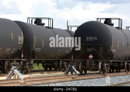 Cisterna nero automobili della ferrovia contenente olio di aspettare di essere scaricati su un lato rampa. Foto Stock