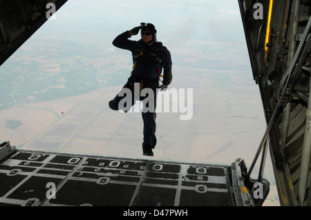 Un U.S. Navy parachute dimostrazione membro del team saluta come egli passi fuori della rampa di un C-130 Hercules aeromobili. Foto Stock