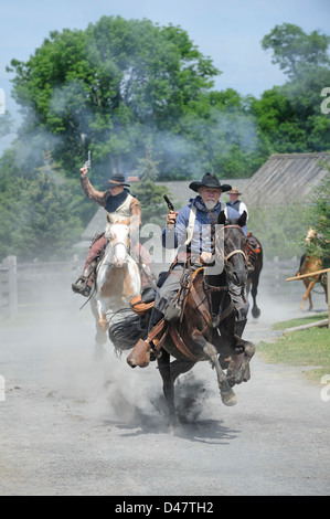 Cowboy a cavallo duro e veloce attraverso la città con sei cannoni sfolgorante, turbolenti fare gli uomini problemi con un sacco di polvere e di azione. Foto Stock