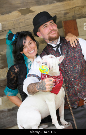 Felice Victorian l uomo e la donna si divertono con i loro bull terrier cane leccare un lecca-lecca. Foto Stock