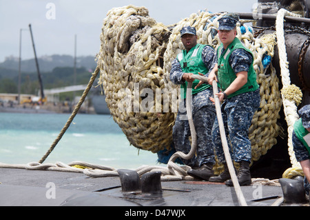 I marinai heave una linea di ormeggio a bordo della USS Columbus. Foto Stock