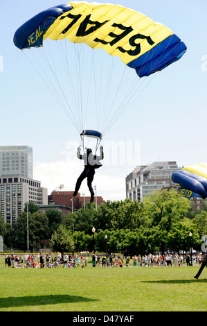 Un membro dell'U.S. Navy Parachute team di dimostrazione, il salto delle rane, terre in Boston Common Boston durante la settimana della Marina. Foto Stock