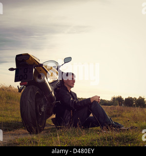 Un giovane uomo che un riposo da un drive sulla sua moto. Foto Stock