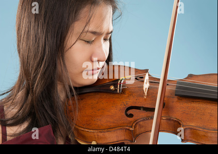 Giovane donna asiatica a suonare il violino su sfondo blu Foto Stock