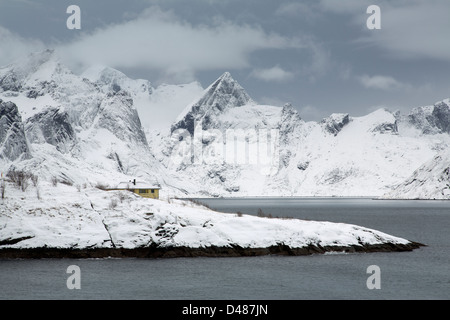 Una tradizionale casa norvegese accanto Reine-Fjorden sulle Isole Lofoten in Norvegia a metà inverno. Foto Stock