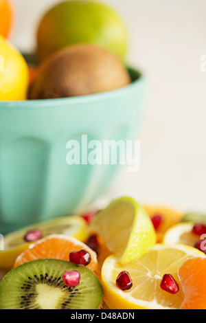 Una ciotola di agrumi, circondato da segmenti di frutta e le fette su un pavimento piastrellato in background Foto Stock