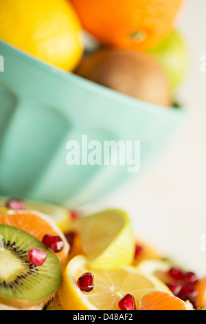 Una ciotola di agrumi, circondato da segmenti di frutta e le fette su un pavimento piastrellato in background Foto Stock