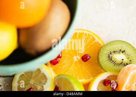 Una ciotola di agrumi, circondato da segmenti di frutta e le fette su un pavimento piastrellato in background Foto Stock