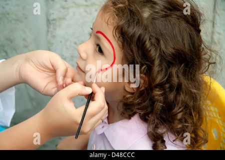 Bambina ottenendo il suo volto dipinto da un artista a un Festival Foto Stock