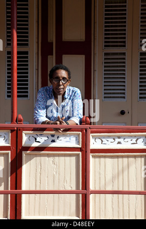 La donna da St Lucia, in piedi sul portico del suo tradizionale casa di legno, Vieux Fort St Lucia Foto Stock