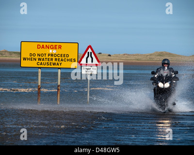 Uomo sulla moto attraversando la strada rialzata a Isola Santa Foto Stock