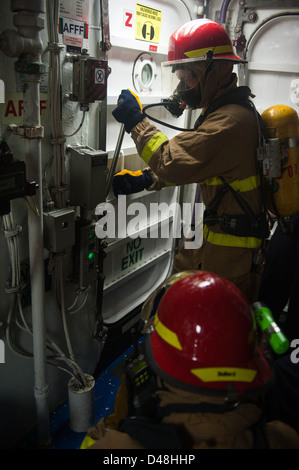I marinai la lotta contro un incendio simulato a bordo della USS Mobile Bay. Foto Stock