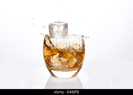 Il cubo di ghiaccio che rientrano in un bicchiere di Whiskey Foto Stock
