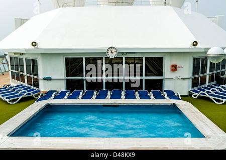 Occupato del bianco e del blu lettini intorno un vuoto di palestra e piscina sul deserto sun deck, in una nebbiosa mattina Foto Stock
