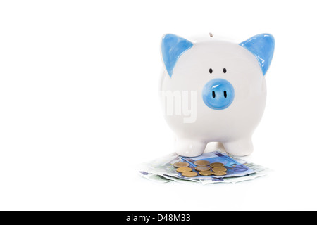 Blu e bianco salvadanaio in piedi sulle banconote e monete in euro Foto Stock
