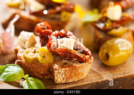 Antipasto Italiano bruschette con olio di oliva, olive, pomodori secchi e formaggio. Foto Stock