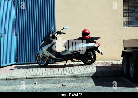 Argento scooter bici del motore con la sicurezza del casco protettivo Foto Stock