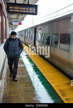 Merrick, New York, Stati Uniti d'America. 8 marzo 2013. Sebbene il Long Island Rail Road pianificare rimane buona malgrado né'Pasqua viscido nevicata venerdì pomeriggio sulla costa sud di Long Island, il freddo umido i venti raggiungono i passeggeri in attesa sotto la sporgenza di protezione al di sopra della piattaforma degli elevati Merrick stazione ferroviaria. Credito: Ann e Parry / Alamy Live News Foto Stock